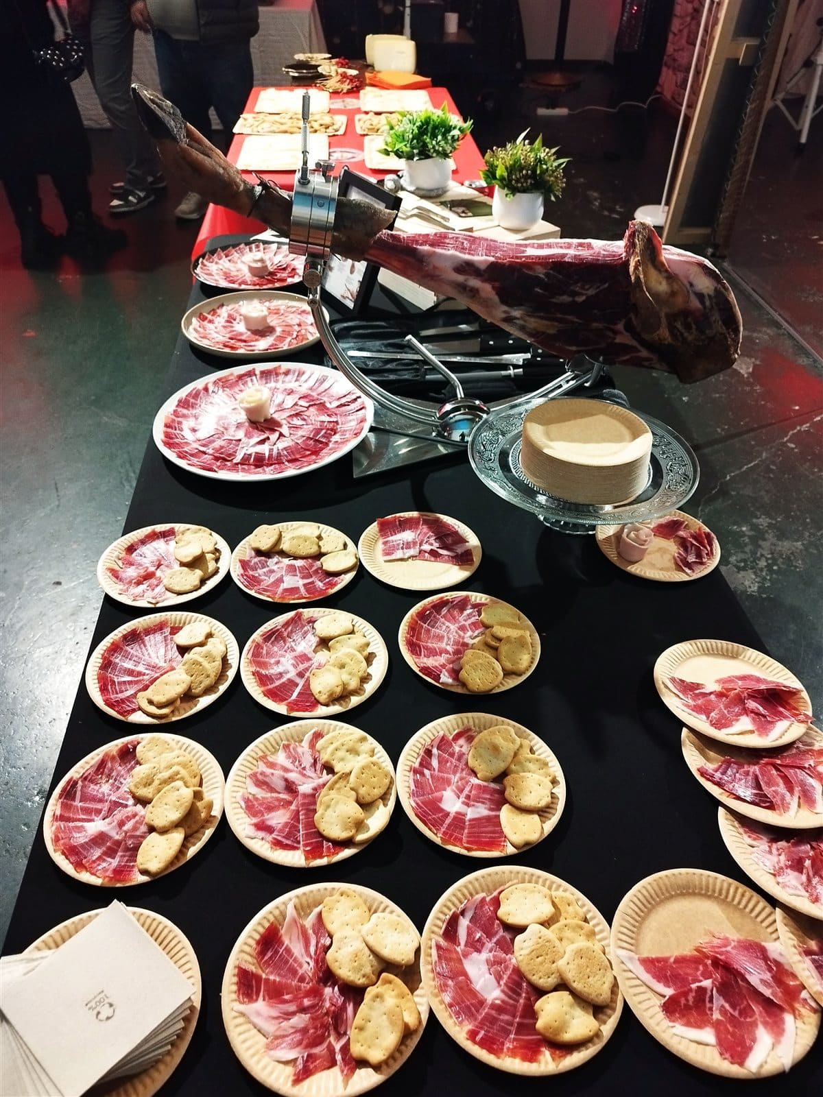 Mesa de presentación con platos de jamón ibérico y acompañamientos en un evento gourmet