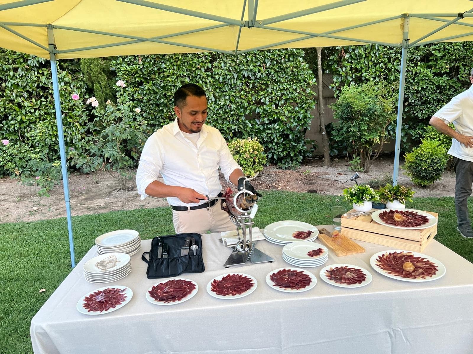 Jeffrey Rodríguez cortando jamón ibérico a cuchillo en un evento privado al aire libre